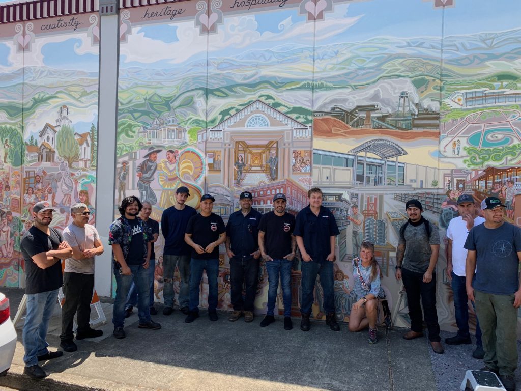 Factory Pipe team in front of depiction of the facility