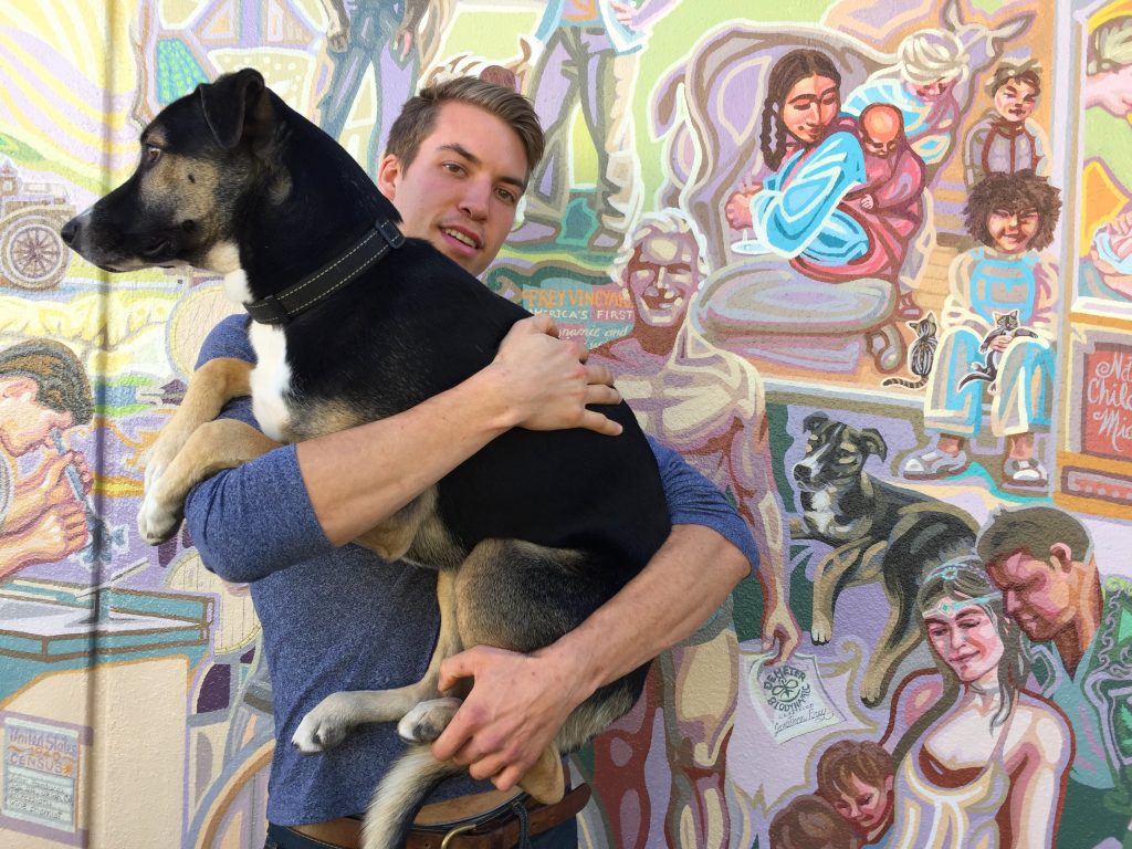 Young man with his dog whose portrait is in the mural