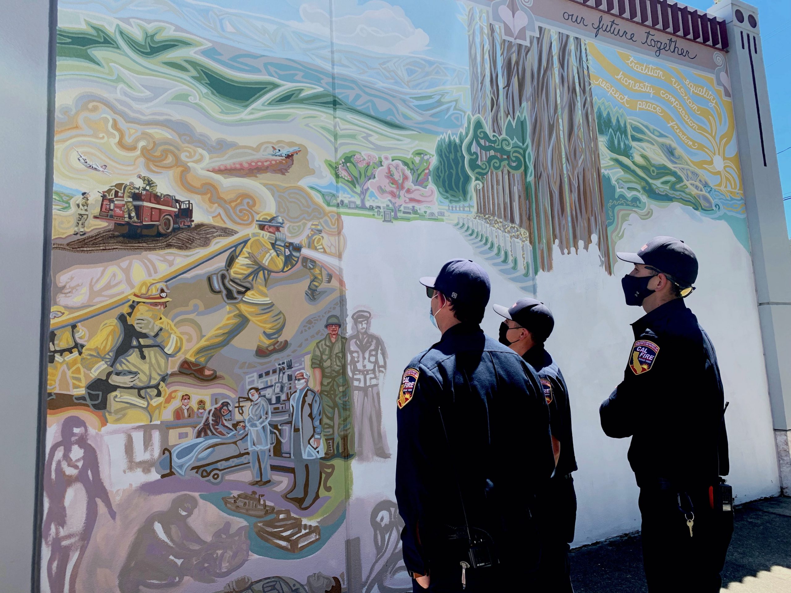 CalFire firefighters look at their representation in the mural.